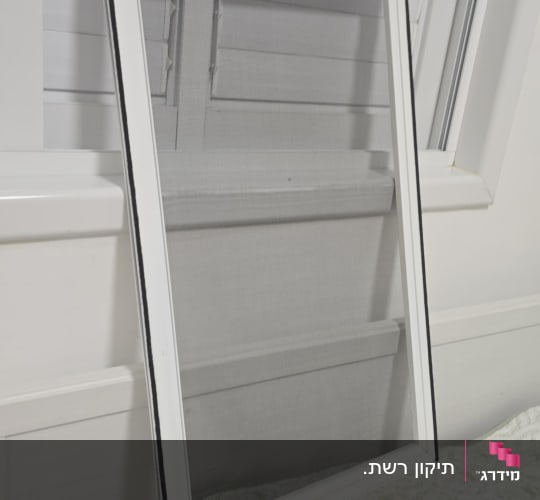 מסגרת חלון עם רשת על מיטה ליד תריסים